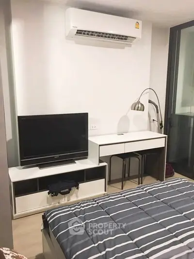 Modern bedroom with TV, desk, and air conditioning in a stylish apartment.