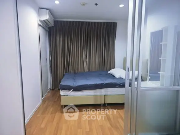 Modern bedroom with wooden flooring and large window, featuring a comfortable bed and stylish decor.