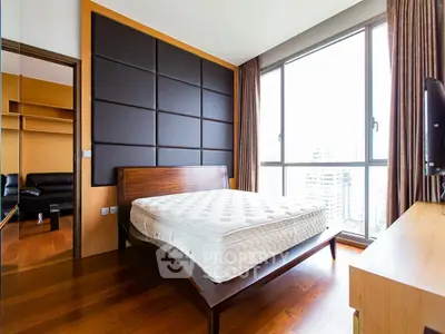 Spacious bedroom with large windows and modern decor in urban apartment.