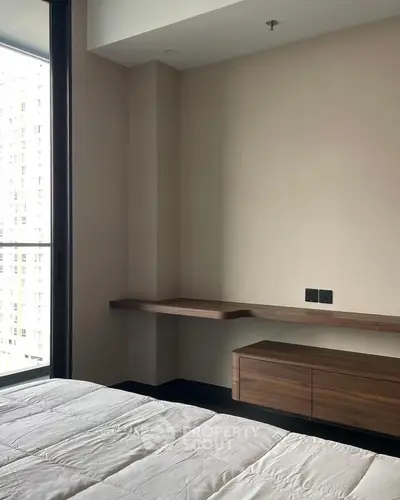 Modern bedroom with sleek wooden furniture and large window view.