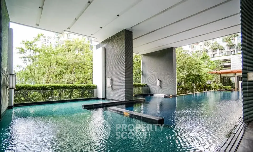 Luxurious modern pool area with lush greenery and sleek architectural design.