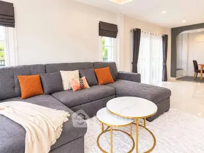 Spacious modern living room with plush gray sectional sofa and elegant round coffee tables.