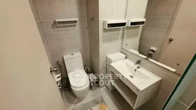Modern bathroom with sleek fixtures and neutral tiles, featuring a compact design and efficient use of space.