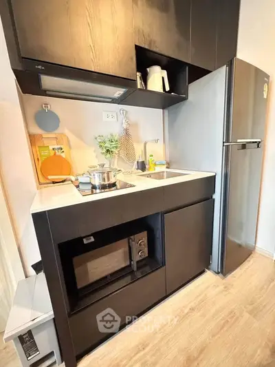 Modern compact kitchen with sleek black cabinets and stainless steel appliances