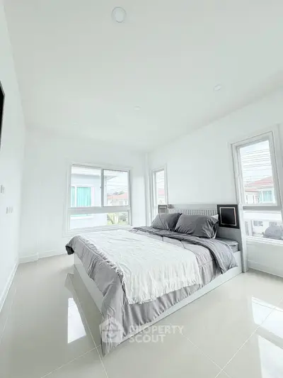 Bright and spacious bedroom with modern decor and large windows offering natural light.