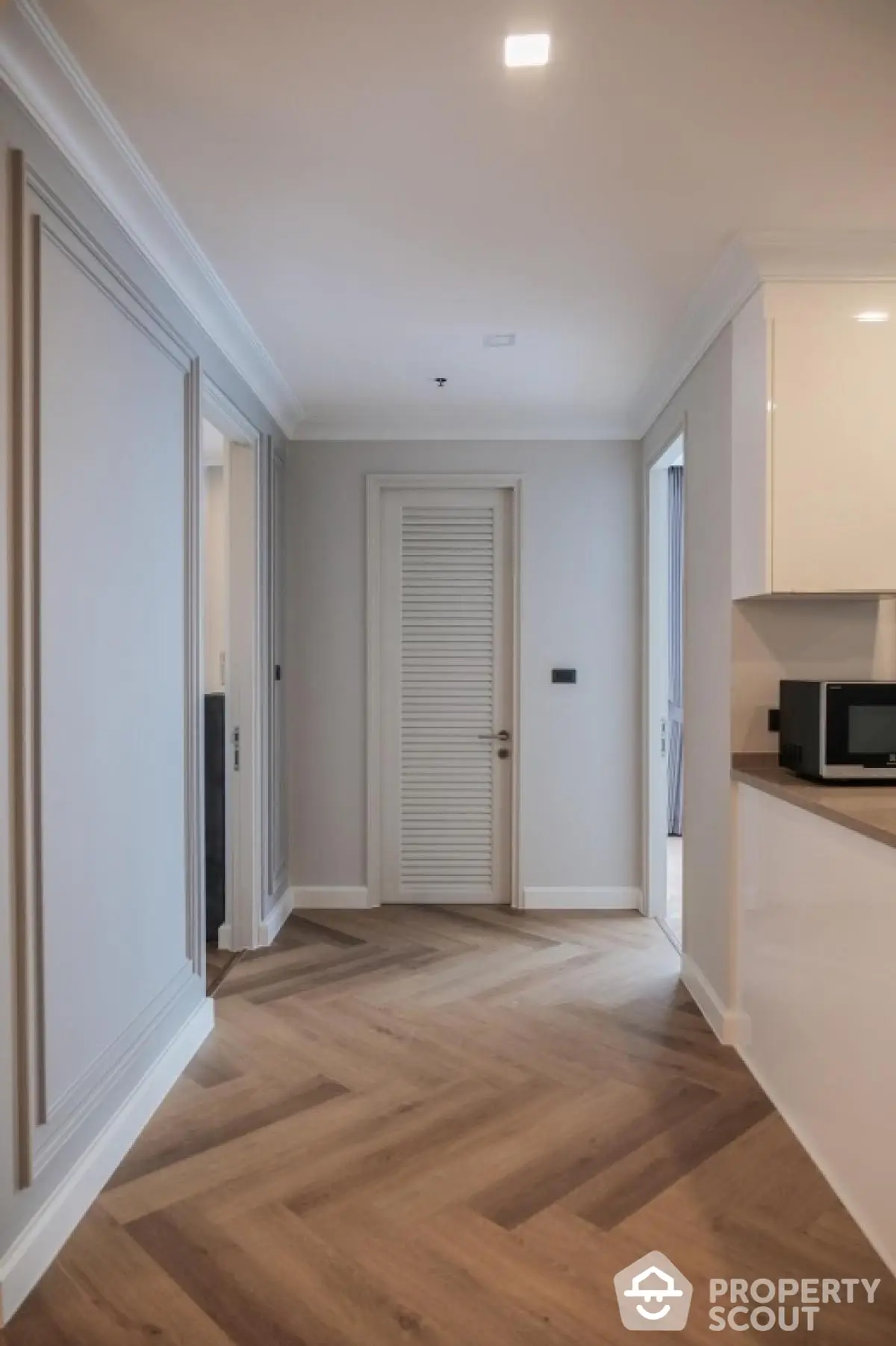 Modern hallway with elegant wood flooring and sleek white cabinetry