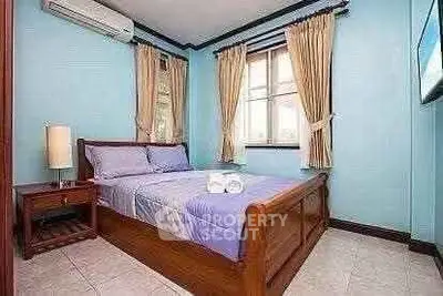 Cozy bedroom with wooden bed frame and blue walls, perfect for relaxation.