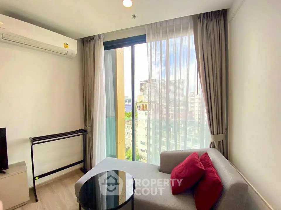 Modern living room with city view, featuring cozy sofa and large window.