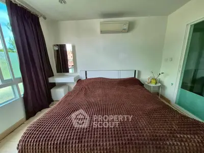 Cozy bedroom with large window and air conditioning, featuring a stylish brown bedspread and modern decor.