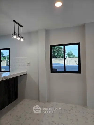 Modern kitchen with sleek lighting and large window offering natural light.