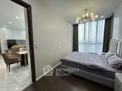 Modern bedroom with elegant lighting and view into stylish living area