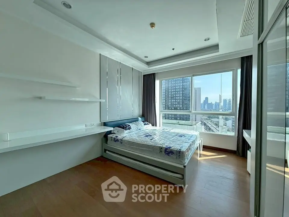 Spacious bedroom with city view and modern furnishings in high-rise apartment