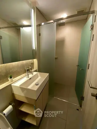 Modern bathroom with sleek sink and glass shower doors, perfect for contemporary living.