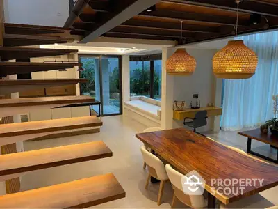 Modern dining area with wooden table, open staircase, and stylish lighting in luxury home.