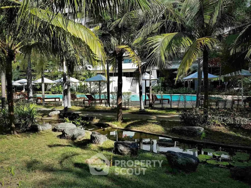 Luxurious tropical garden with poolside view and palm trees in a serene residential complex.