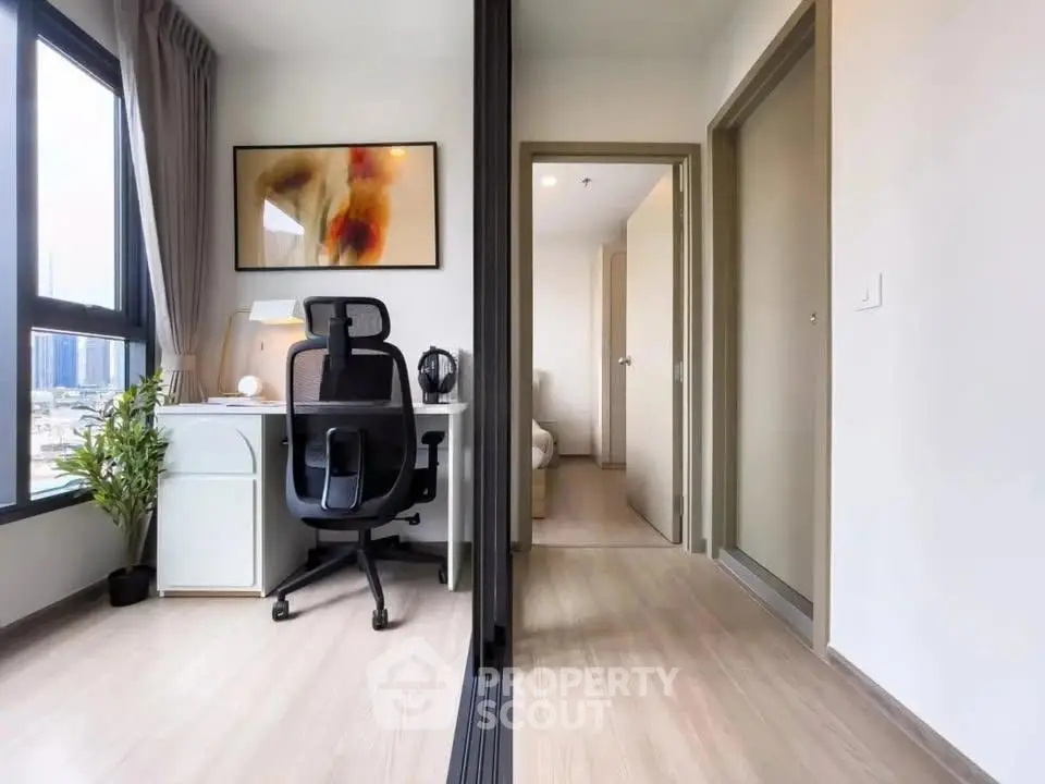 Modern apartment with study area and bedroom, featuring sleek design and natural light.
