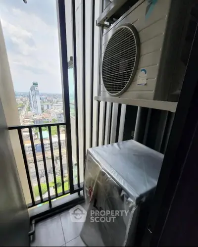 Compact balcony with city view and air conditioning unit in modern high-rise apartment.