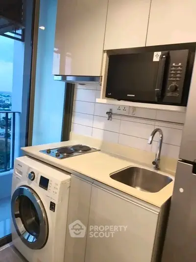 Modern kitchen with sleek appliances and city view from balcony.