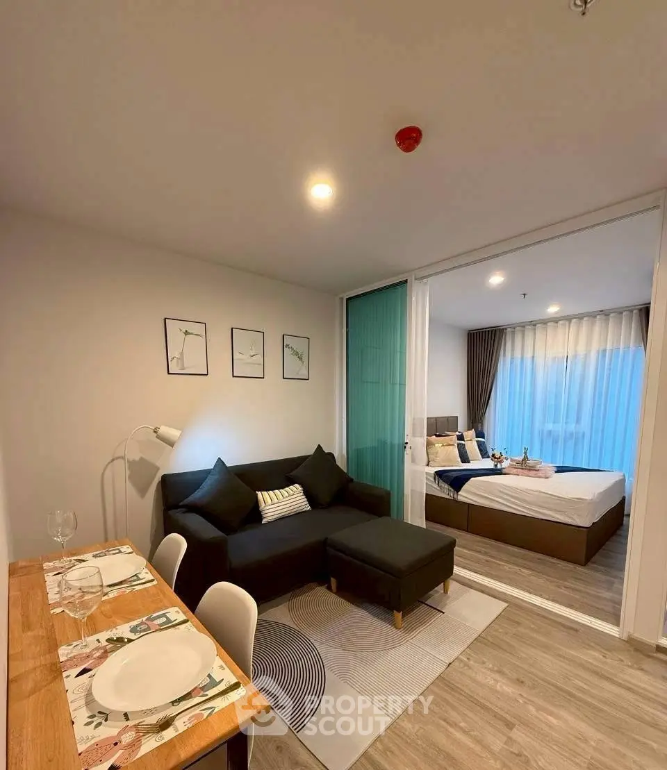 Modern open-plan living room with cozy dining area and stylish bedroom view.