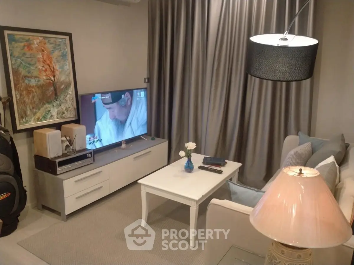 Cozy living room with modern decor, featuring a flat-screen TV, elegant lighting, and a stylish coffee table.