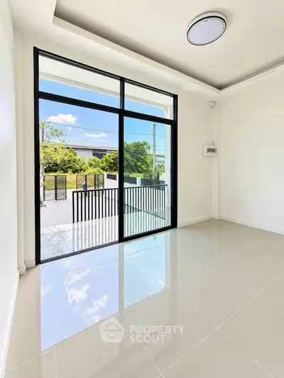Bright and spacious room with large glass doors leading to a sunny outdoor area, perfect for modern living.