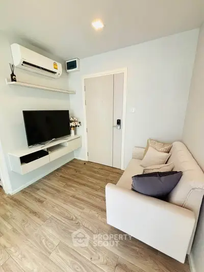 Modern living room with sleek design, featuring a cozy sofa, wall-mounted TV, and air conditioning.