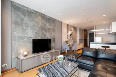 Modern living room with sleek design and open kitchen layout, featuring a stylish leather sofa and marble accents.