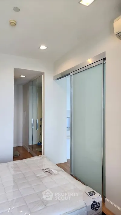 Modern bedroom with sliding glass door and mirrored closet in a bright apartment.