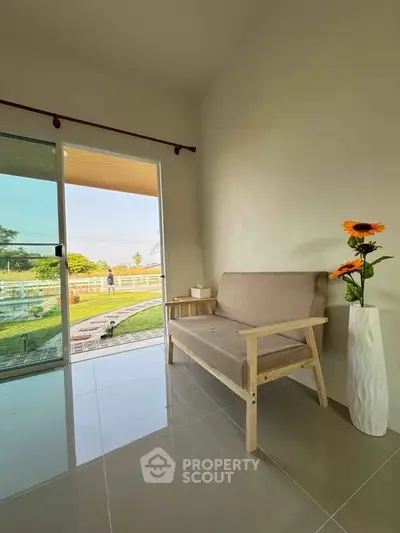 Cozy living room with sliding glass door opening to a scenic garden view, featuring a modern sofa and elegant vase.