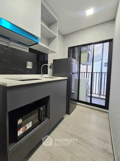 Modern kitchen with sleek black cabinetry and balcony view