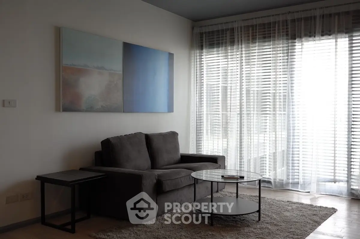 Modern living room with cozy sofa, stylish coffee table, and large window with sheer curtains.