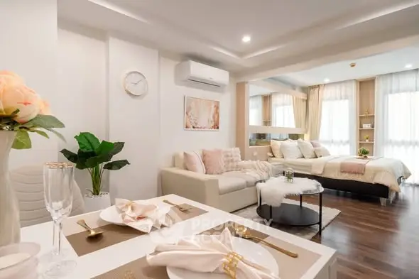 Luxurious open-plan living room and bedroom with elegant decor and natural light.