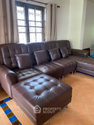 Spacious living room with elegant brown leather sectional sofa and tiled flooring.