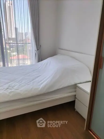 Cozy bedroom with city view, featuring a comfortable bed and modern decor.