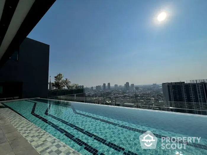 Stunning rooftop pool with panoramic city skyline view under clear blue sky.