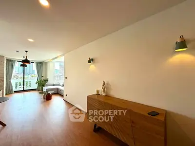 Spacious modern living room with wooden flooring and city view balcony.