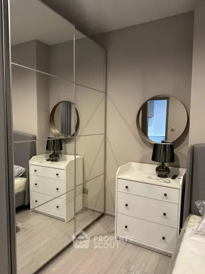 Modern bedroom with mirrored wardrobe and stylish dresser in a cozy apartment.