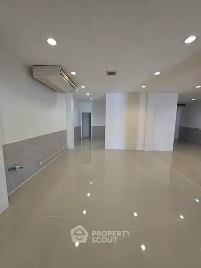 Spacious modern interior with sleek tiled flooring and recessed lighting, perfect for versatile living or office space.