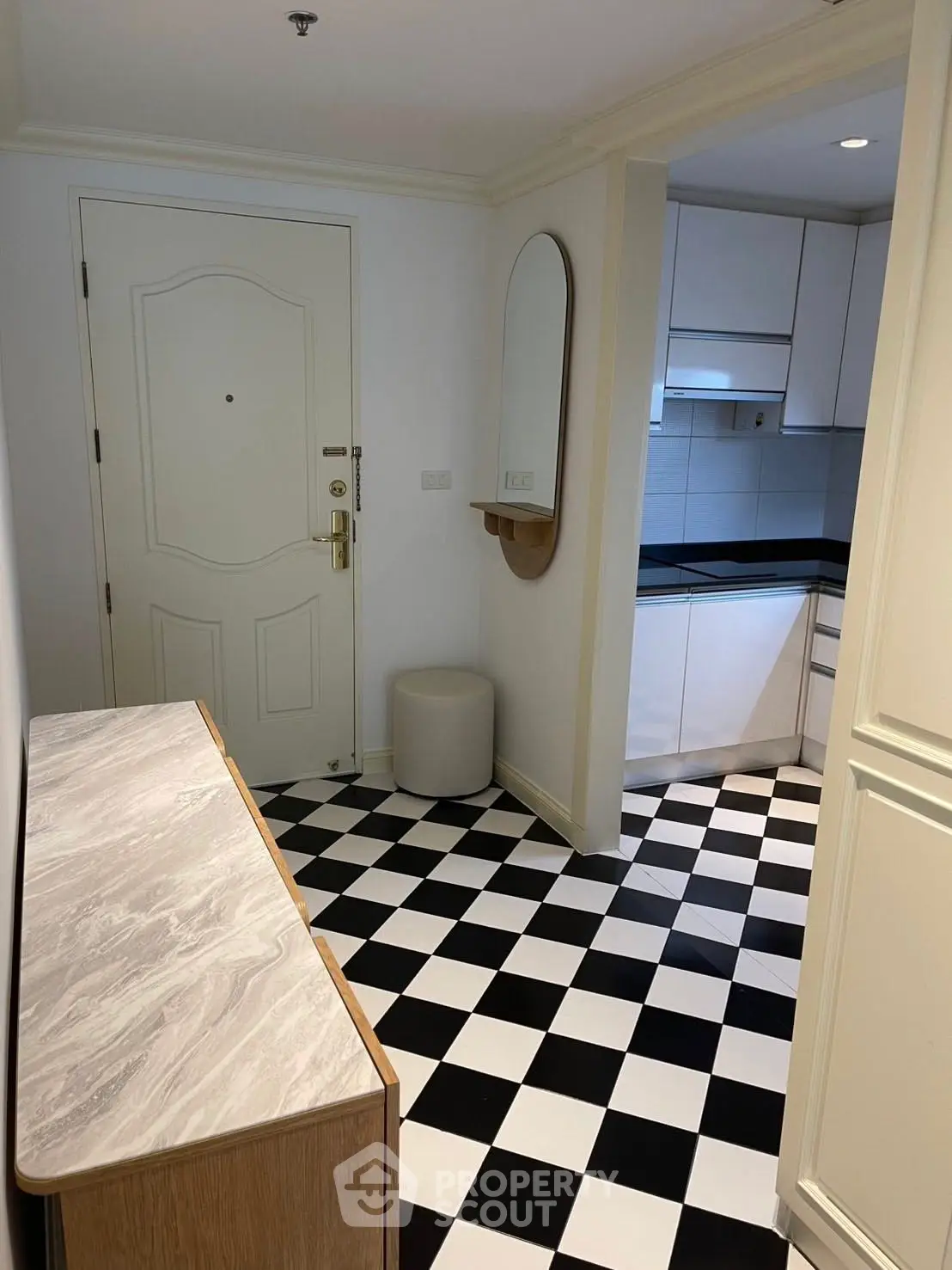 Chic entryway with black and white checkered floor leading to a modern kitchen.