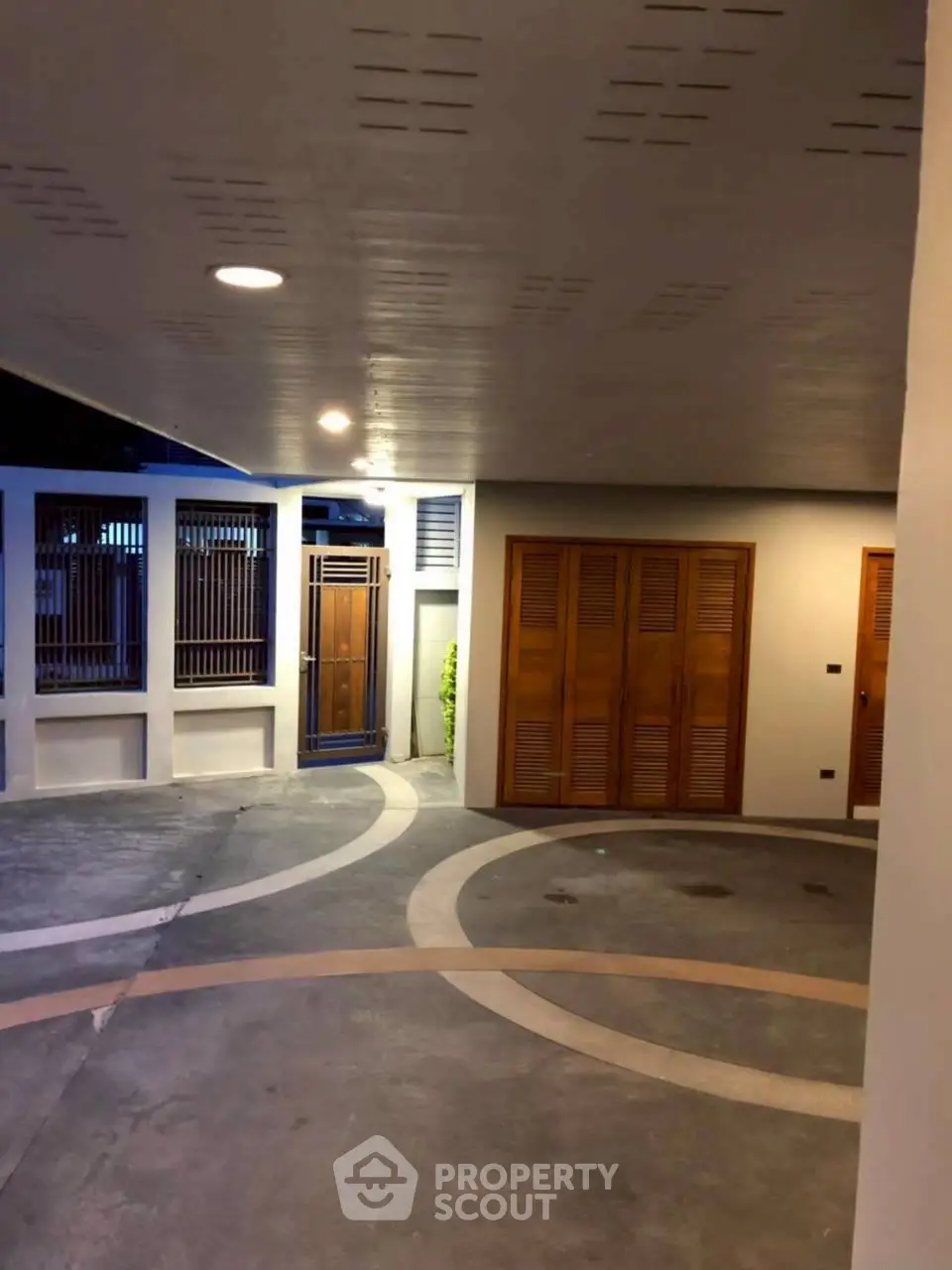 Stylish modern entrance with wooden doors and unique circular driveway design.