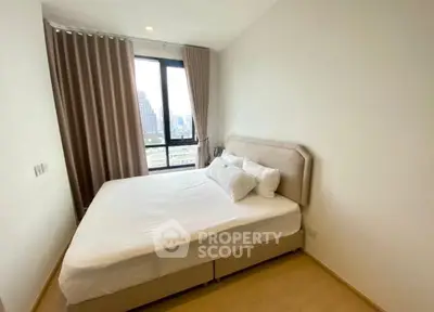 Cozy bedroom with city view, featuring a comfortable bed and large window with curtains.
