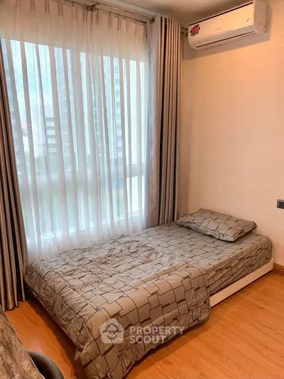 Cozy bedroom with single bed and air conditioning, featuring floor-to-ceiling windows and elegant curtains.