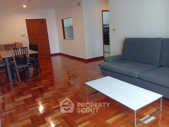 Spacious living room with wooden flooring and modern furniture in a stylish apartment.