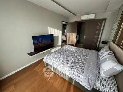 Modern bedroom with stylish decor, featuring a wall-mounted TV and sleek wooden flooring.