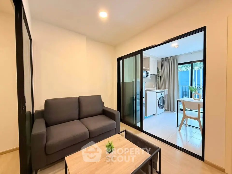 Modern living room with sliding doors leading to a bright kitchen and dining area.