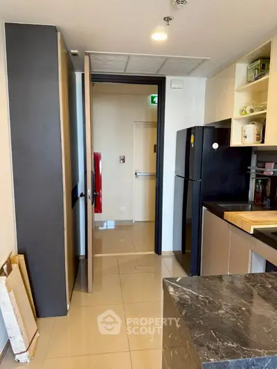 Modern kitchen with sleek black appliances and marble countertop in a stylish apartment.