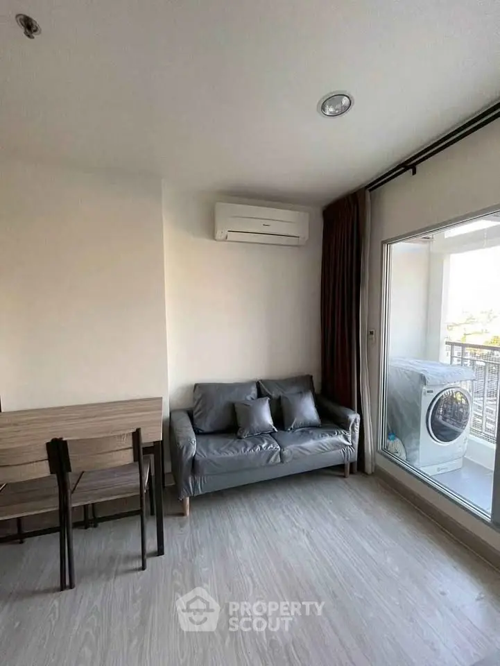 Modern living room with balcony and washing machine, featuring sleek furniture and air conditioning.