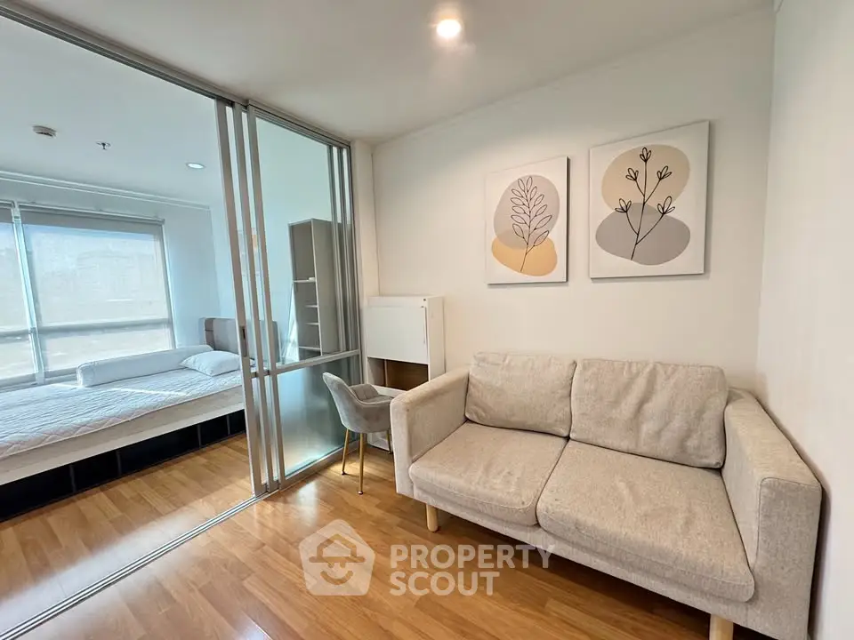 Modern apartment with cozy living room and bedroom separated by glass partition, featuring stylish decor.