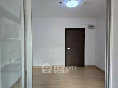 Minimalist empty room with wooden flooring and dark wooden door, ideal for customization.