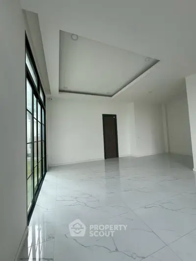 Spacious modern living room with large windows and sleek marble flooring